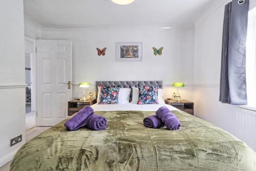 um quarto com uma cama grande e almofadas roxas em Elegant 3 Bedroom House in Basildon - Essex Free Parking & Superfast Wifi, upto 6 Guests em Basildon