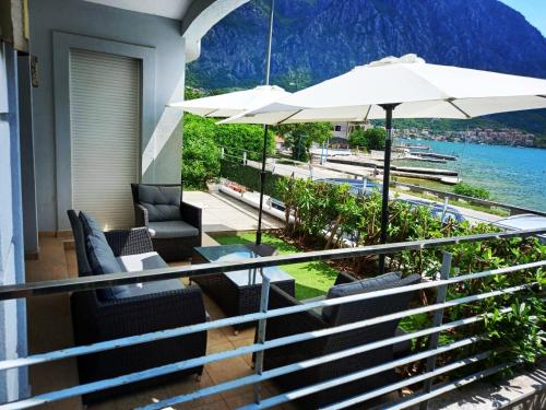 - un balcon avec des chaises, un parasol et l'eau dans l'établissement Ariya mare apartman Risan Montenegro, na plaži, à Risan
