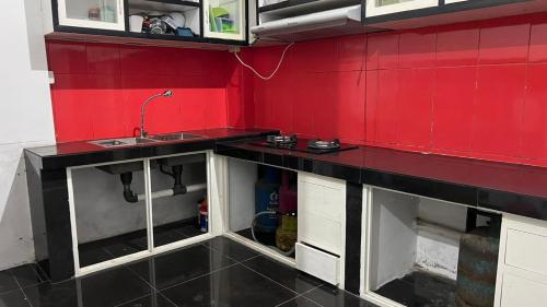 eine Küche mit einem Waschbecken und einer roten Wand in der Unterkunft RUMAH 25 SYARIAH in Bukittinggi