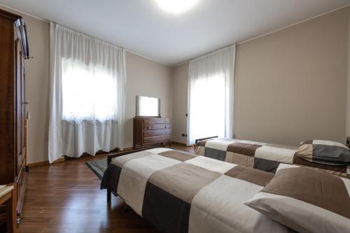 a bedroom with two beds and a dresser and two windows at Nonna Elvira Holiday House in Bondone