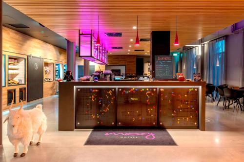 a restaurant with a bar with a display of food at Moxy London Excel in London