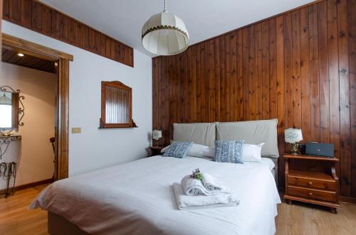 - une chambre avec un lit blanc et un mur en bois dans l'établissement Appartamento centralissimo con wi-fi, à Cortina dʼAmpezzo