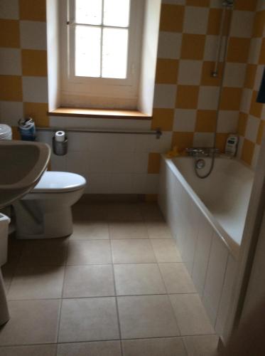 een badkamer met een bad, een toilet en een raam bij Chambres d'hôtes au calme 