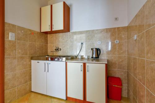una pequeña cocina con armarios blancos y fregadero en Rooms and Apartments Oregon, en Budva