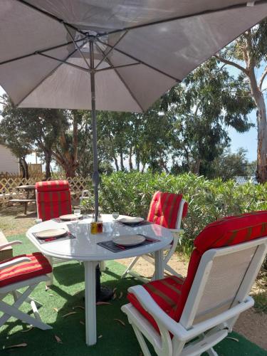 une table blanche avec deux chaises et un parasol dans l'établissement LAVATOGGIO, à Lumio