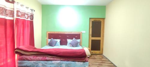 a bedroom with a bed with a red head board at Noor Guest House in Leh