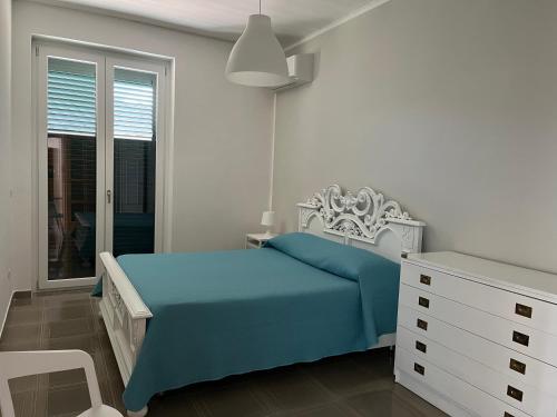 a white bedroom with a blue bed and a window at Villa Claudia - casa vacanze in Agropoli