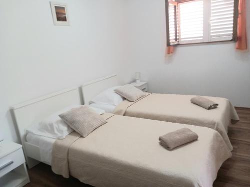 Duas camas num quarto com paredes brancas e uma janela em Studio apartment Novak em Cilipi