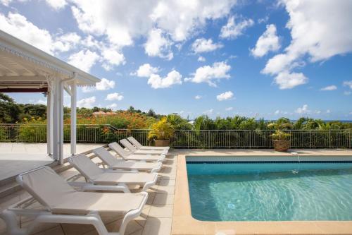 a swimming pool with lounge chairs next to a fence at Villa Madras in Les Terres Basses