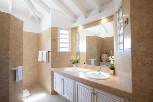 a bathroom with two sinks and a large mirror at Villa Madras in Les Terres Basses