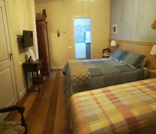 una camera d'albergo con due letti e una televisione di Cà Nostra B&B Home Restaurant a Portacomaro