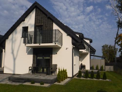 a white house with a balcony and a yard at Villa Luis in Dziwnów