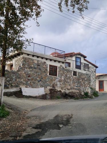 a stone house with a balcony on top of it at THE ROCK HOUSE - Beautiful countryside with mandarins oranges and olive trees,. Near Limassol at Eptagonia village. in Ephtagonia