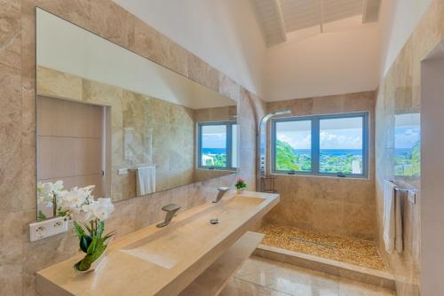 La salle de bains est pourvue d'un grand lavabo et d'un grand miroir. dans l'établissement Villa El Grande Azure, à Baie Longue