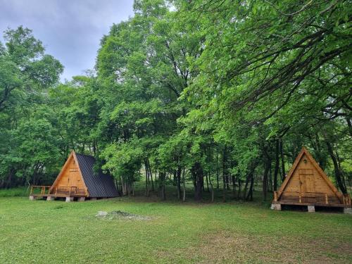 two small wooden houses in a field with trees at Wolf & Sheep Nature & Adventure in Podgorica