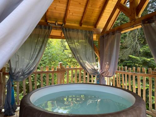 a hot tub on a deck with a wooden fence at Les Lodges de Babylone in Larringes