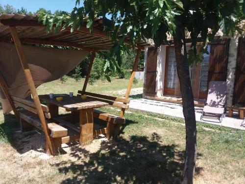 a hammock and a table in front of a house at maisonnette le cabanon in Sainte-Jalle