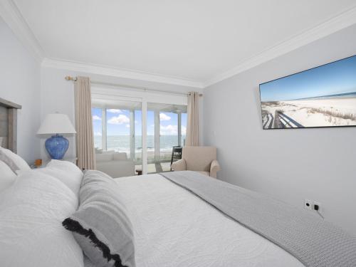 a bedroom with a white bed with a view of the ocean at El Mar Villa in Ponte Vedra Beach