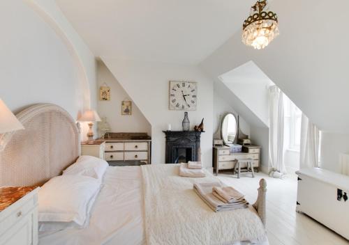a white bedroom with a large bed and a clock at Upper Nestleton Maisonette in Swanage