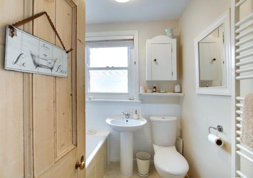 a bathroom with a toilet and a sink and a window at Upper Nestleton Maisonette in Swanage