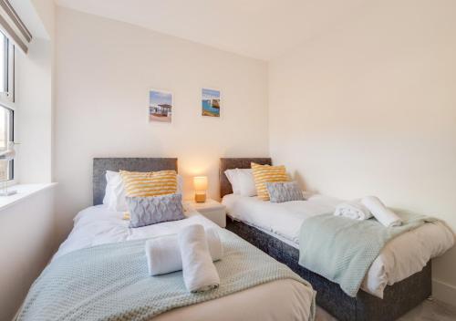 Duas camas num quarto com paredes brancas em Victoria Sands em Swanage