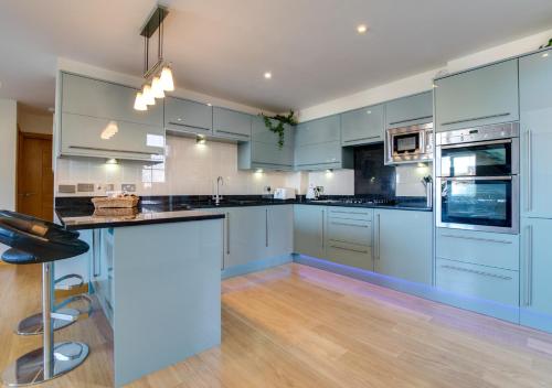 a large kitchen with blue cabinets and a counter at Tuppence View in Swanage