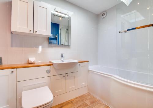 uma casa de banho com um WC e uma banheira. em Tuppence View em Swanage