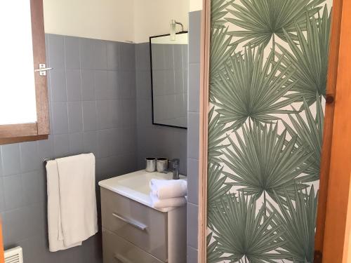 a bathroom with a green leaf patterned shower curtain at la dolce farniente in Biaudos