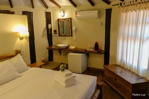 a bedroom with a bed with a sink and a mirror at Pousada Villa Luna in Penedo