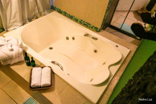 a bath tub in a bathroom with towels on the floor at Pousada Villa Luna in Penedo