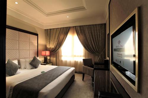 a hotel room with a bed and a flat screen tv at Boudl Kuwait Al Fahahil in Kuwait