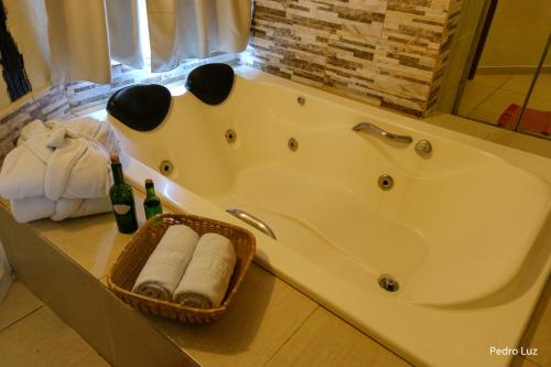 a bathroom with a tub with towels and a bottle of champagne at Pousada Villa Luna in Penedo