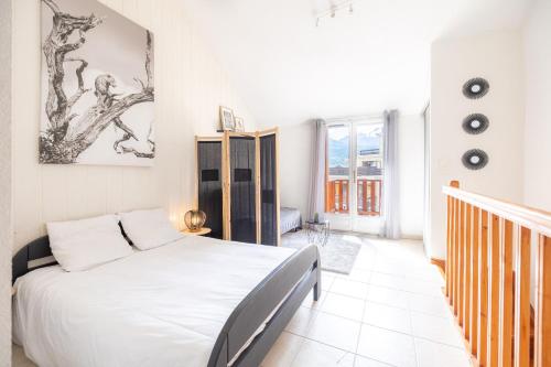 - une chambre blanche avec un lit et un escalier dans l'établissement Charmante maison contemporaine idéalement située, à Embrun