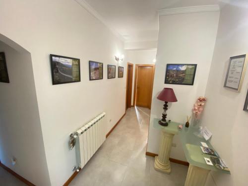 a hallway with white walls and a table and a lamp at Cantinho Do Paul in Arouca