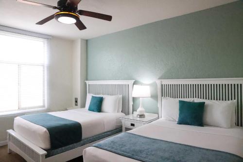 a bedroom with two beds and a ceiling fan at Hotel Carmel Santa Monica in Los Angeles