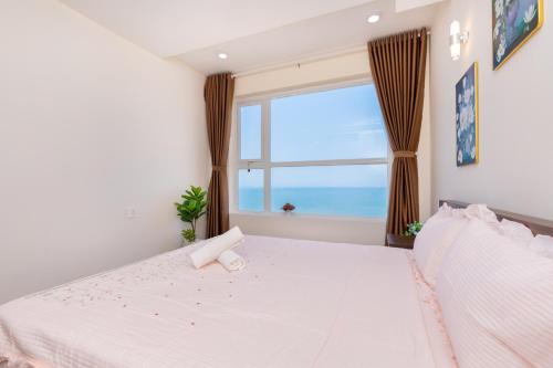 a bedroom with a large white bed with a window at Căn hộ OASKY 2 phòng ngủ view biển ngay quảng trường Vũng Tàu in Vung Tau