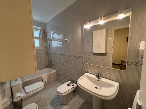 een badkamer met een wastafel, een toilet en een spiegel bij Hostal Zurich in Sant Feliu de Guixols