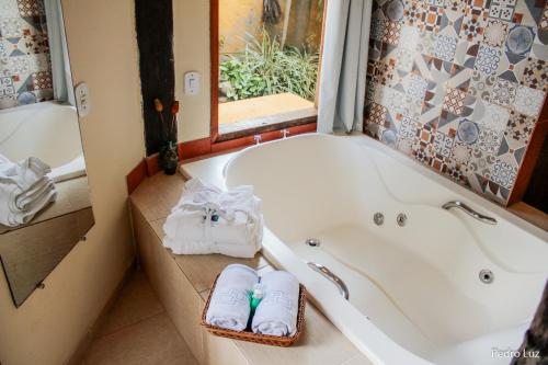 a bathroom with a tub with towels in it at Pousada Villa Luna in Penedo