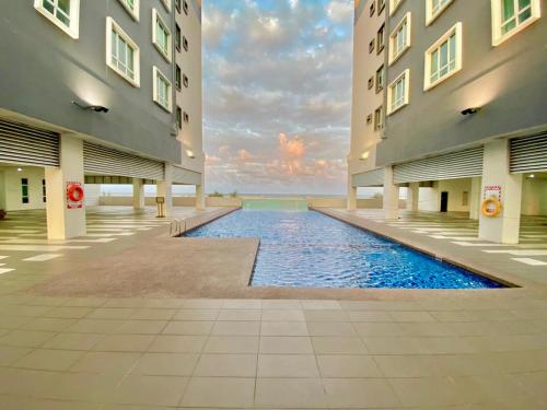 a swimming pool in the middle of two buildings at 4 Bedroom SeaView Ladang Tanjung Apartment - Ayla Homestay in Kuala Terengganu