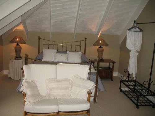 1 dormitorio con 1 cama y 1 silla blanca en Knysna River View Apartment, en Knysna