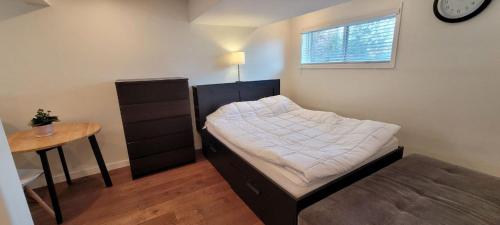 1 dormitorio con cama, mesa y reloj en Private Studio Apartment House, en Calgary