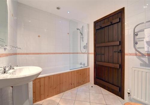 een badkamer met een bad, een wastafel en een douche bij Dale End Barn in Grasmere