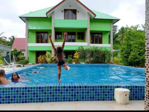 a man jumping into a swimming pool at Benjamine's Guesthouse in La Digue