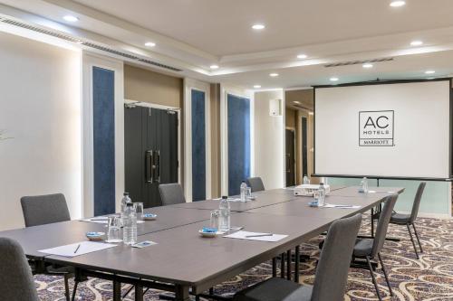 a meeting room with tables and chairs and a projection screen at AC Hotel by Marriott Penang in Bayan Lepas