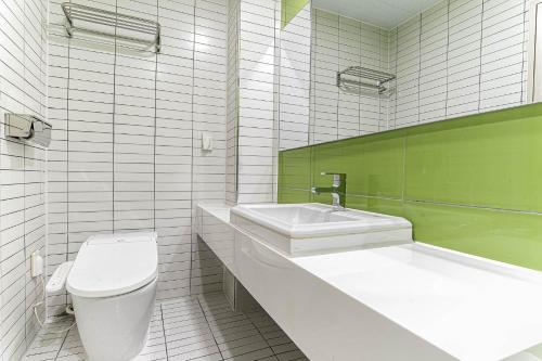 a white bathroom with a toilet and a sink at H Avenue Hotel Idae Shinchon in Seoul
