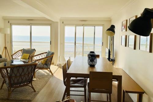 una sala de estar con mesa y sillas y el océano en Appart T4 lumineux avec terrasse vue mer, en Le Touquet-Paris-Plage