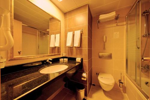 a bathroom with a sink and a toilet and a mirror at Grand Pasa Hotel in Marmaris