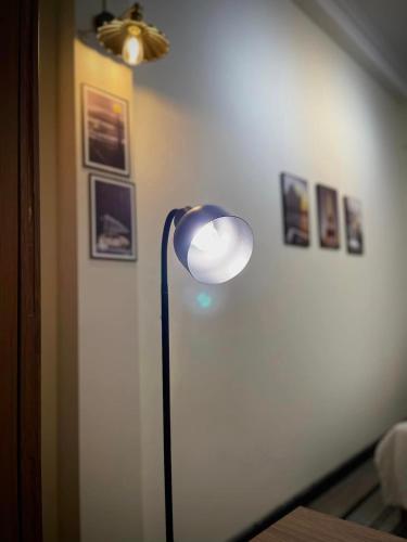 a lamp in a room with a wall with pictures at BÊ TÔNG RESIDENCES HOMESTAY in Can Tho