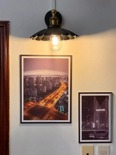 a picture hanging on a wall with a light at BÊ TÔNG RESIDENCES HOMESTAY in Can Tho