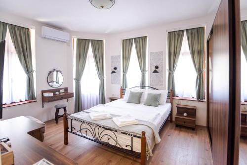 a bedroom with a bed and a desk and windows at City House Central in Bitola